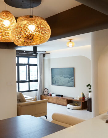 Warm-toned HDB living room with natural lighting, wood finishes, and rattan pendant light.