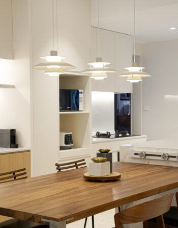 Warm dining area with wooden table and modern pendant lights.